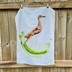 Tea towel with a curlew bird design hanging on a wooden fence