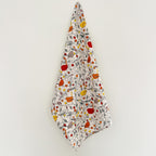 Floral and bird patterned tea towel hanging on a white background