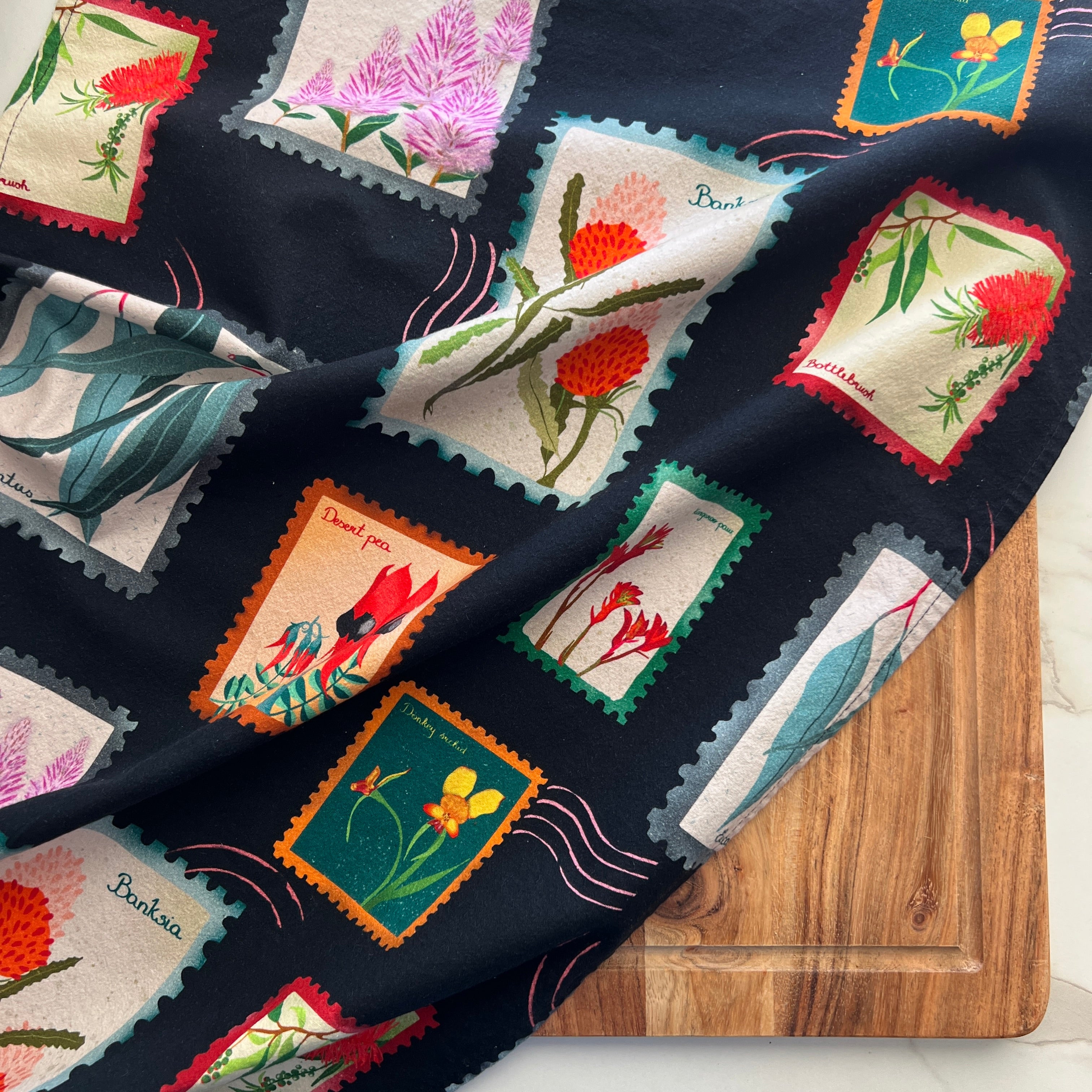 Australian wildflowers tea towel on black background with vibrant native botanical art.