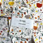 artistic birds tea towel in autumn colours in woodland setting