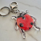 Keychain with a red ladybug design on a light gray background
