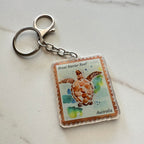 Keychain with a turtle design inspired by a Great Barrier Reef stamp on a light background