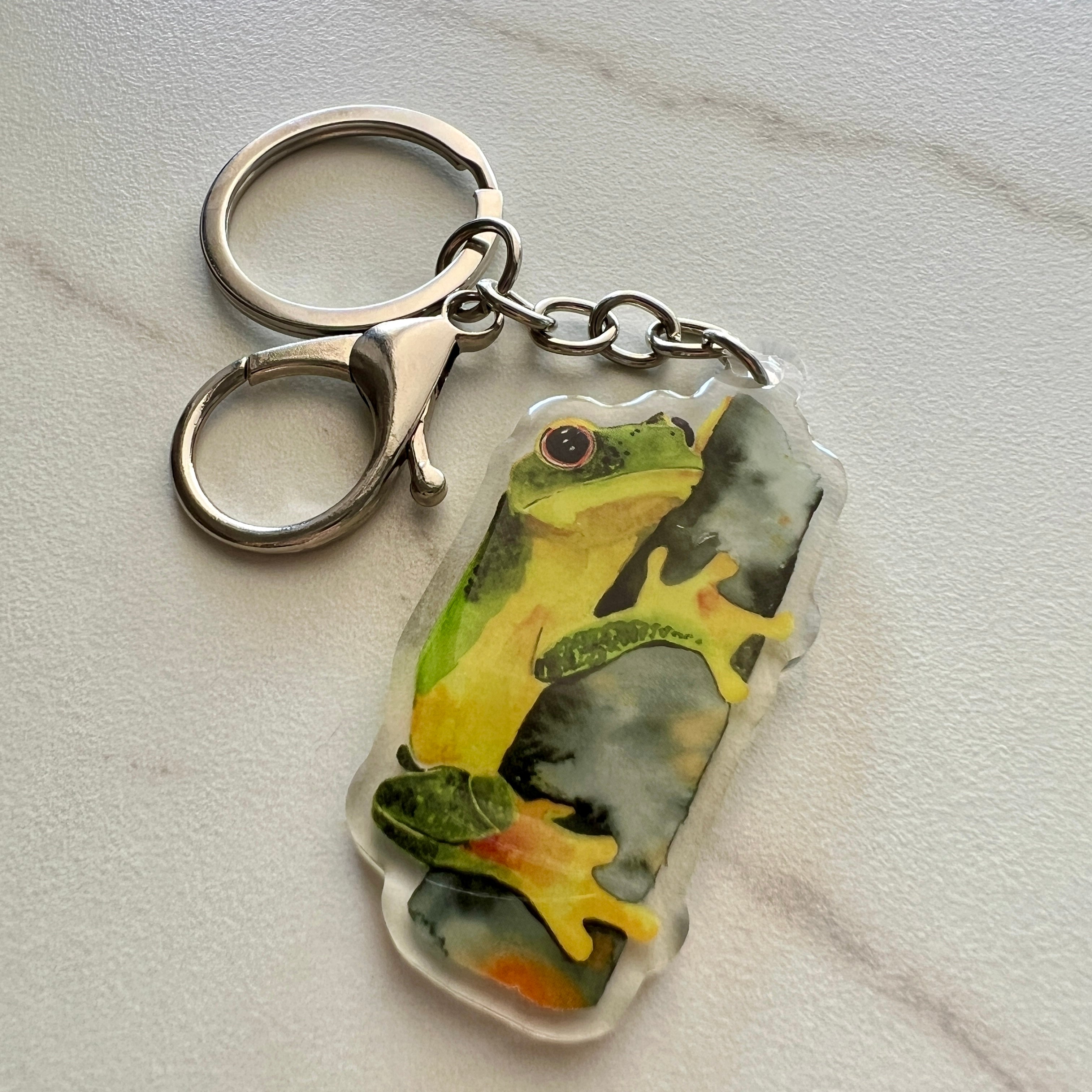 Keychain with a green tree frog design on a light gray background