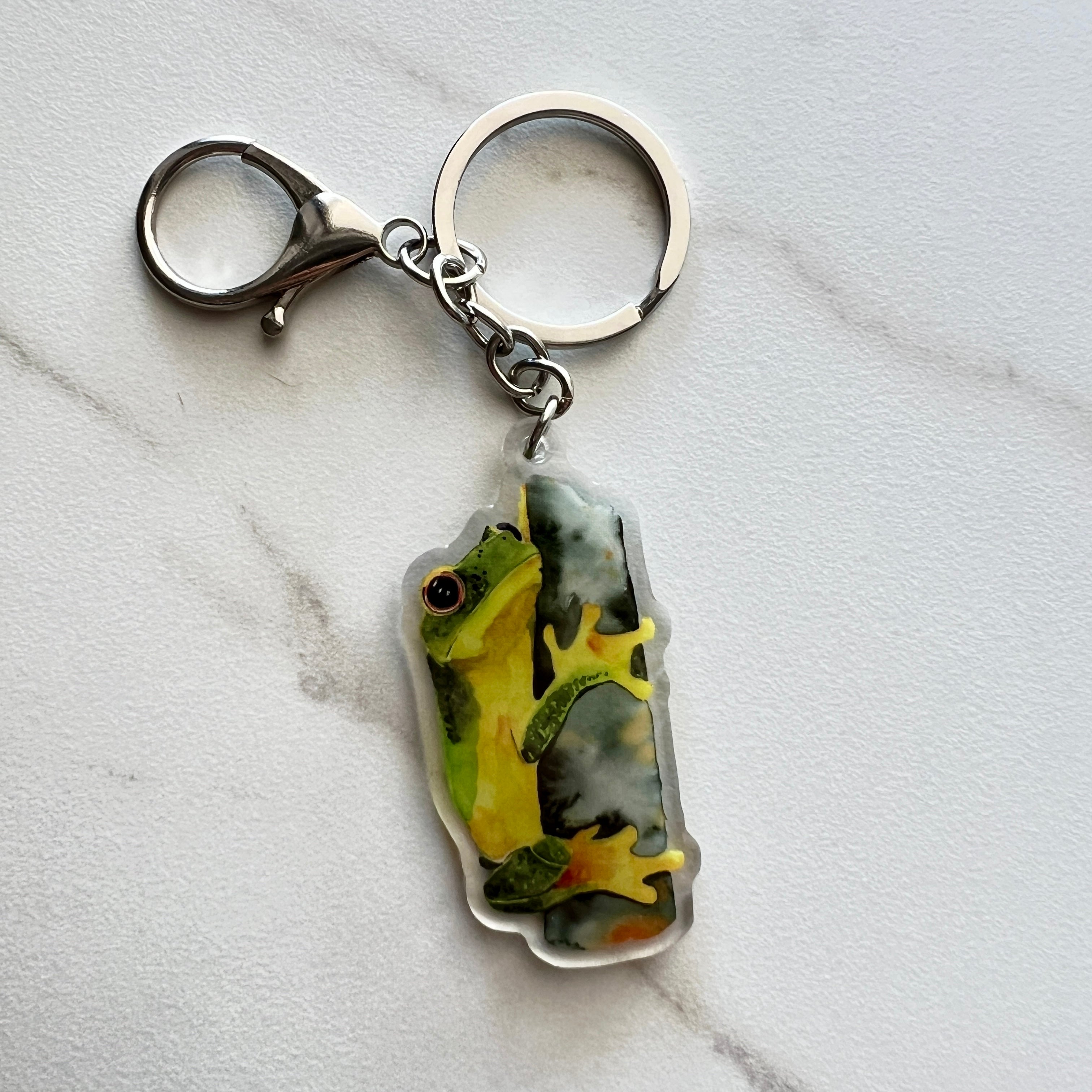 Keychain with a tropical green tree frog design on a marble surface