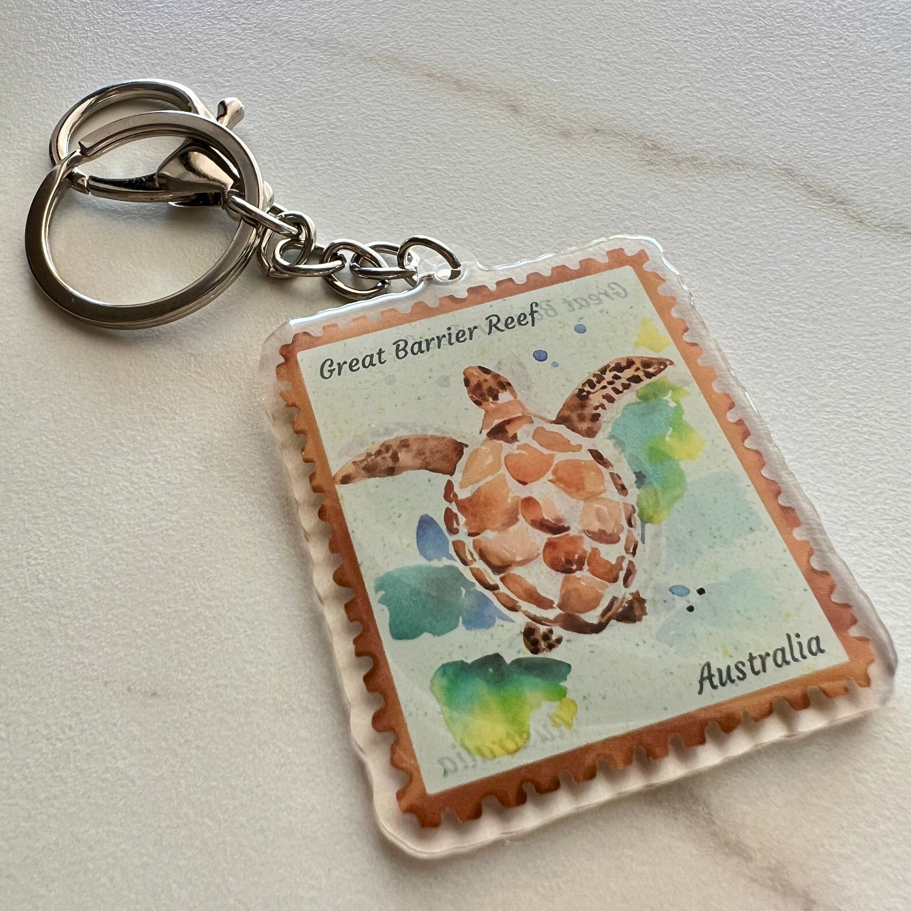 Keychain with a turtle design inspired by a Great Barrier Reef stamp from Australia on a light background.