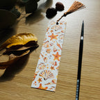 Bookmark with sea-themed design on a wooden surface with leaves and a paint brush.