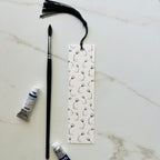watercolour puffin bookmark with tassel on light background with paint brush and paint tubes 